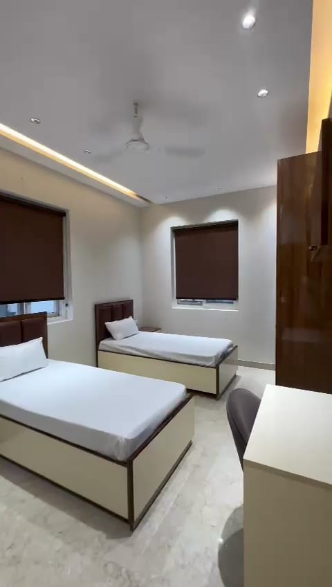 Modern twin beds with blackout blinds at Aden Homez